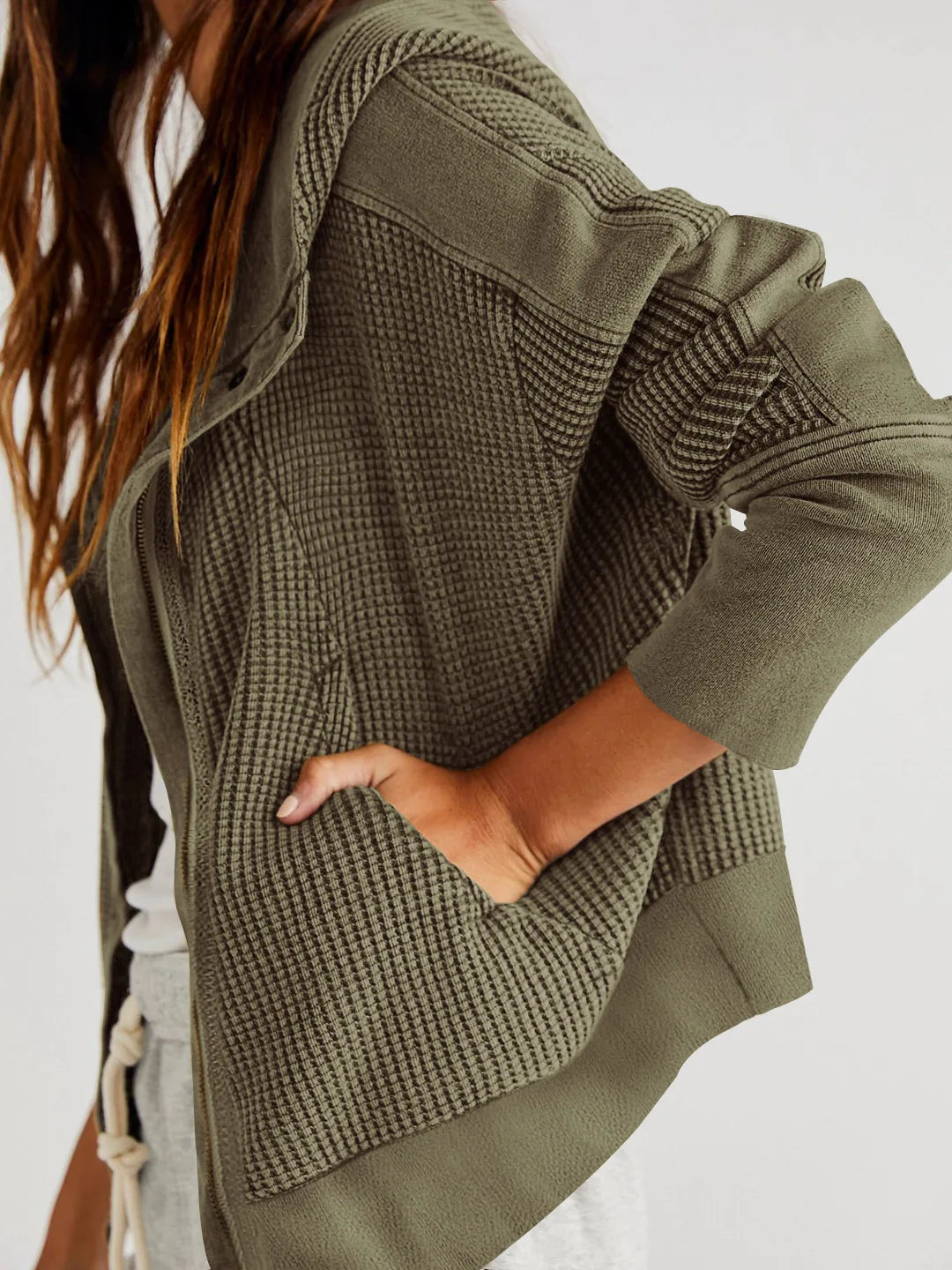 Full-length shot of a woman in a trendy cropped waffle-knit zip hoodie and jeans