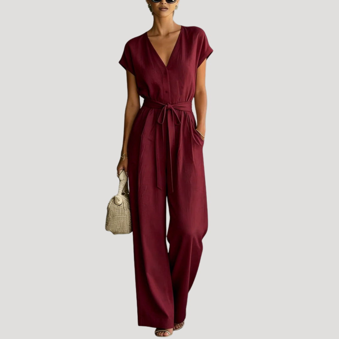 Full-length women's V-neck wide leg jumpsuit, showcasing tie waist detail & cap sleeves, chic and modern.