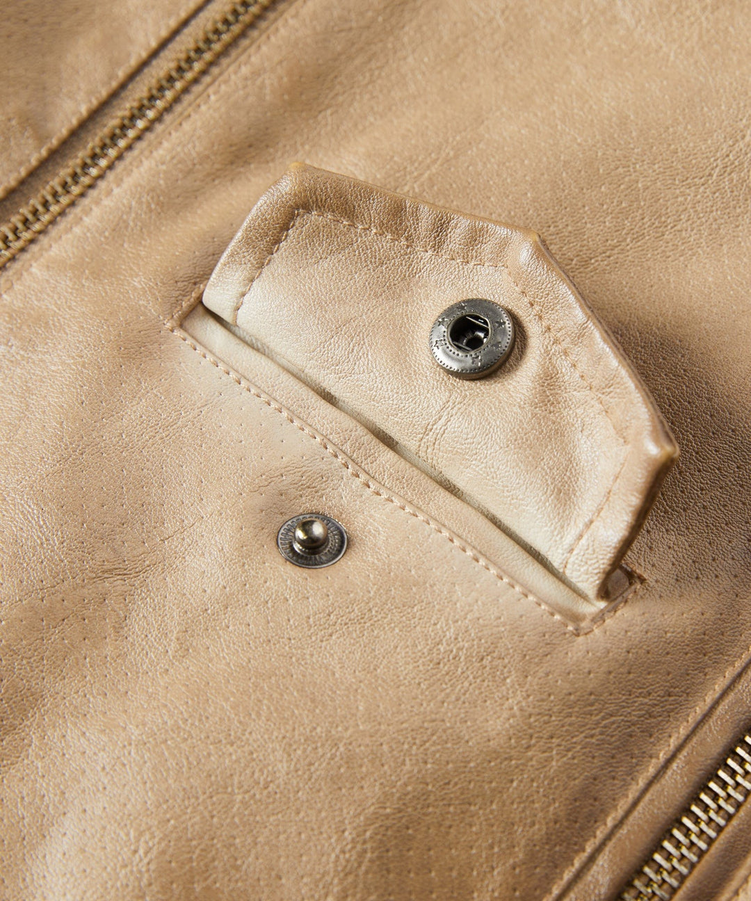 Detail shot of the sleeve and cuff of a women's faux leather jacket, exuding classic and modern style.