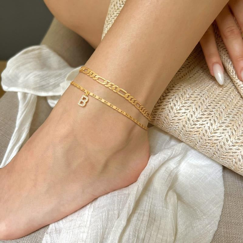Multiple women's gold initial anklets with crystal charms on models, personalized jewelry
