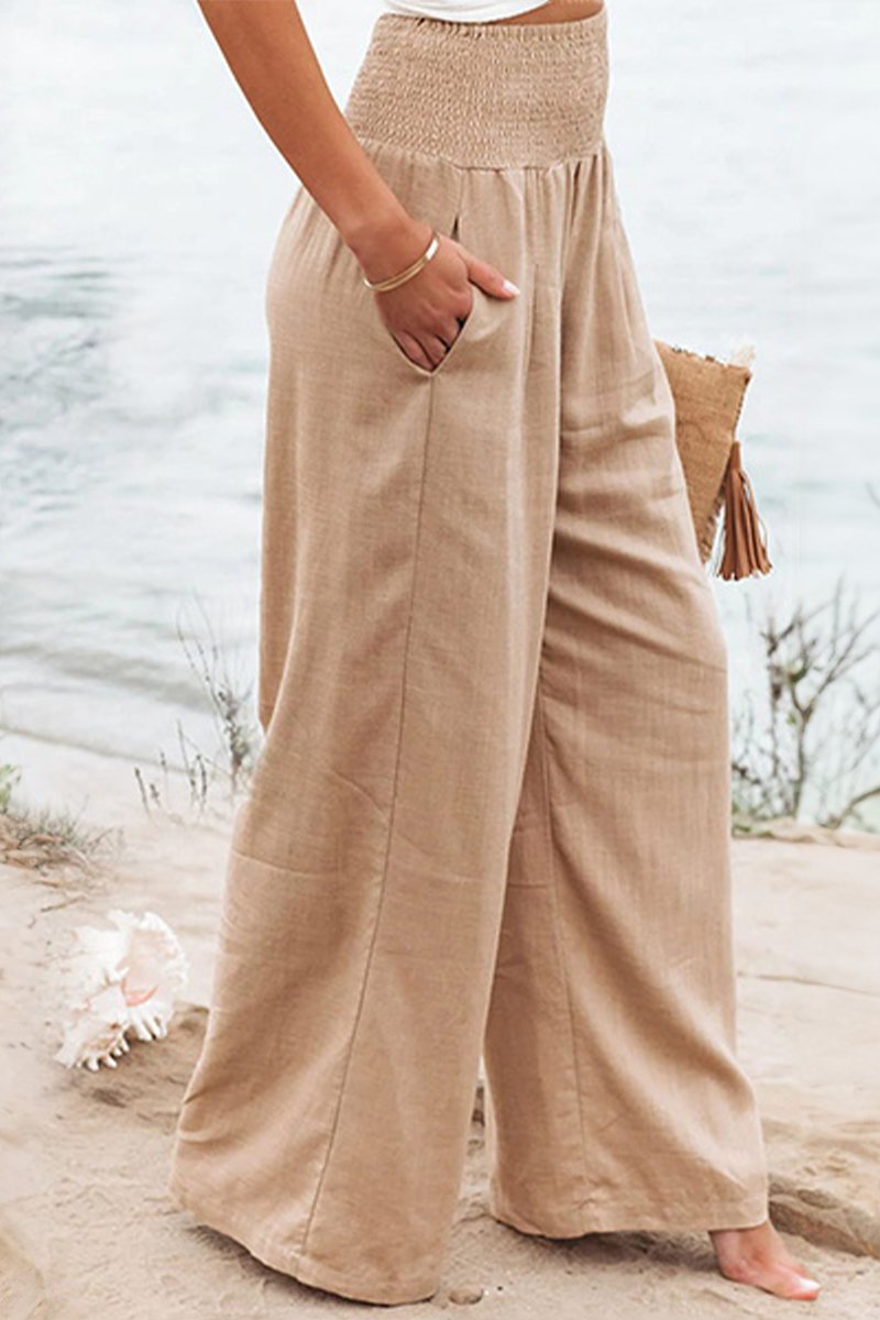 Flowing linen wide-leg pants with a high smocked waist, perfect for comfortable summer wear.