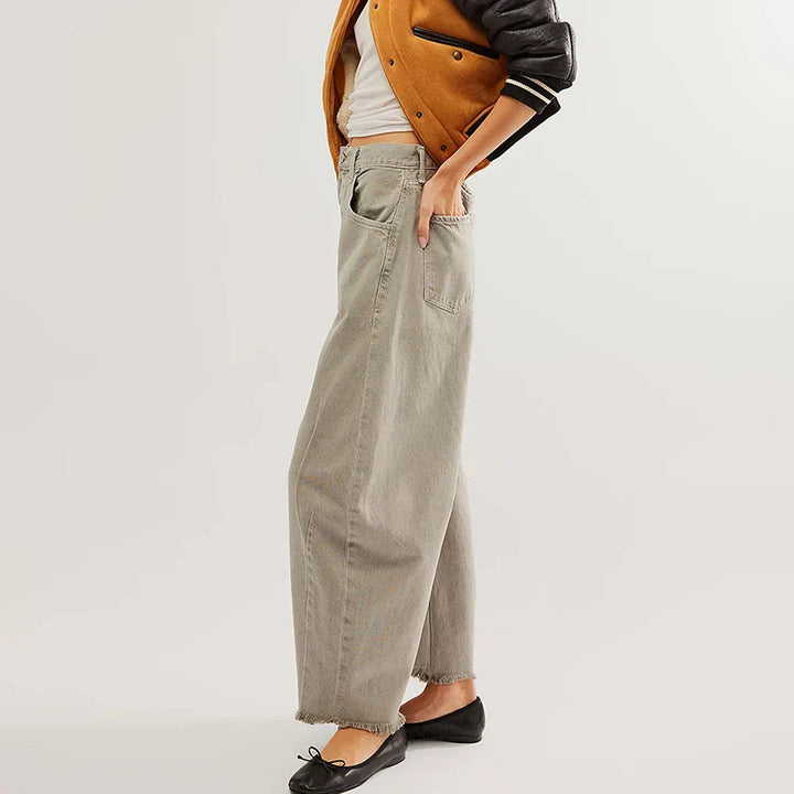 Detailed texture of the organic denim in women's loose fit high-rise jeans with a frayed straight leg.