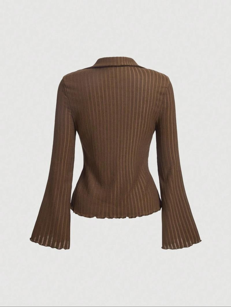 Close-up of a women's ribbed knit blouse with unique flared sleeves, showcasing fabric detail. Versatile fashion.