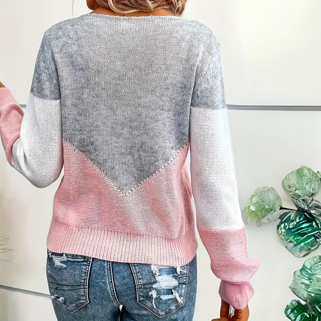 Close-up of a women's knit top, showcasing the intricate mesh detail and soft color block pattern