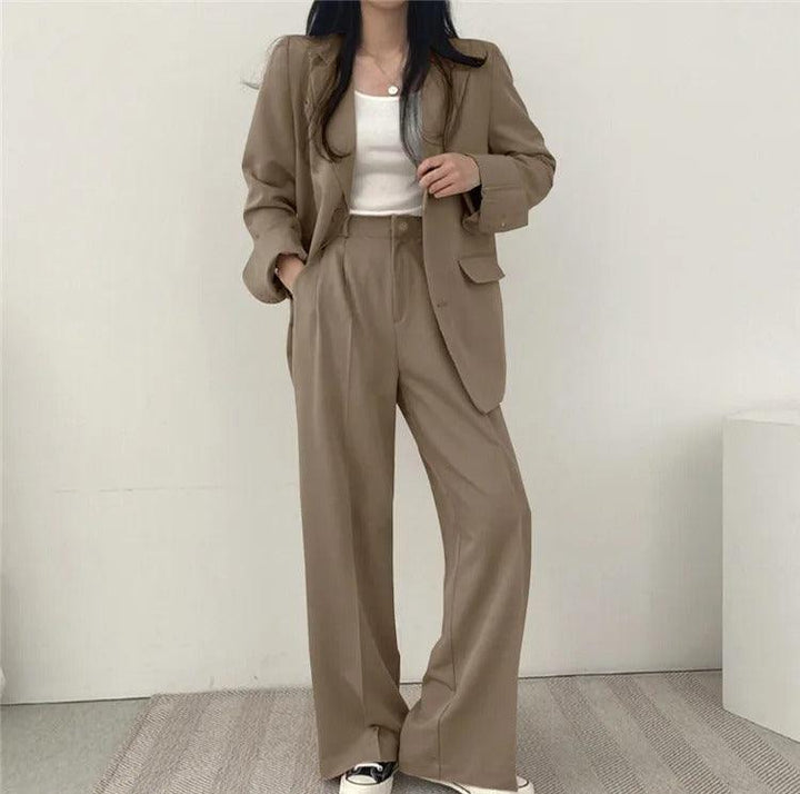 Minimalist women's tailored suit set, featuring a long blazer and clean-cut trousers for a sharp look.
