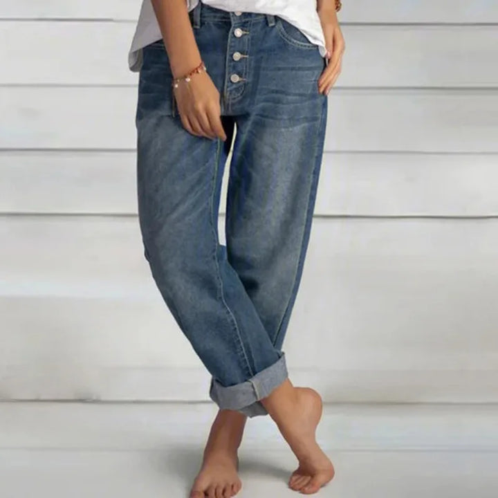 Close-up of the button-front detail on women's relaxed fit blue jeans, highlighting the trendy denim fabric.