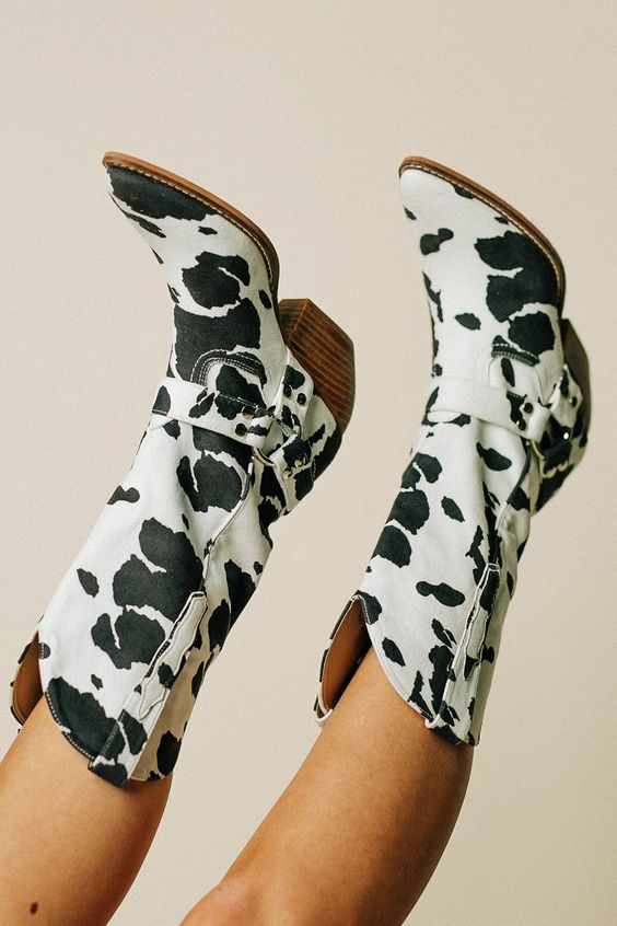 Detailed view of women's cow print belted boots, showcasing Western style and mid-heel