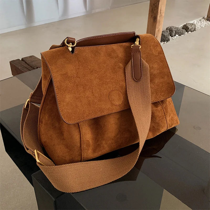 Close-up of a minimalist women's brown suede crossbody bag, showcasing textured material and elegant design
