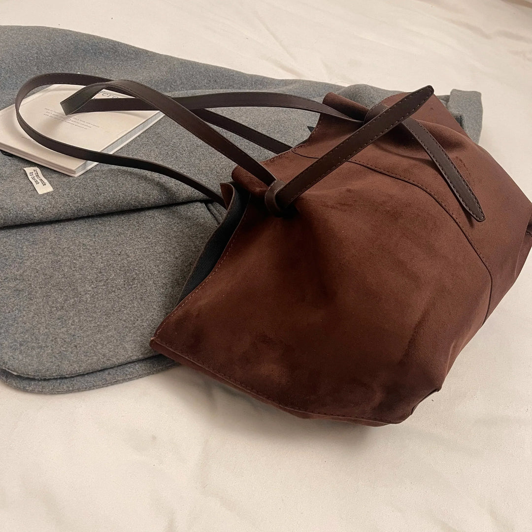 Detail of women's faux suede tote handbag stitching and hardware, high-quality, durable design