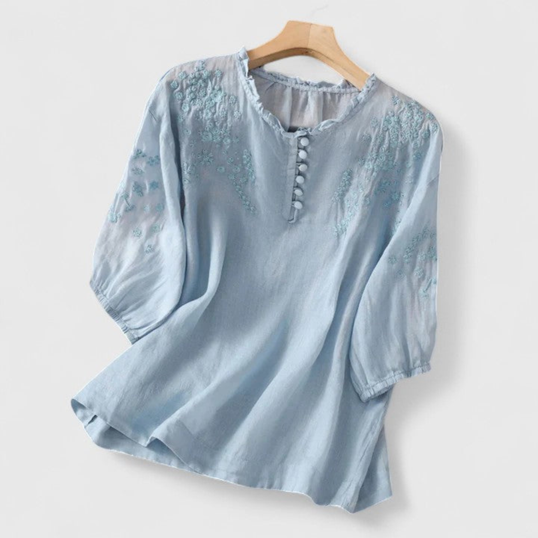 Lightweight women's summer blouse, white, featuring delicate floral embroidery, a chic ruffle collar, and cute pom-poms.